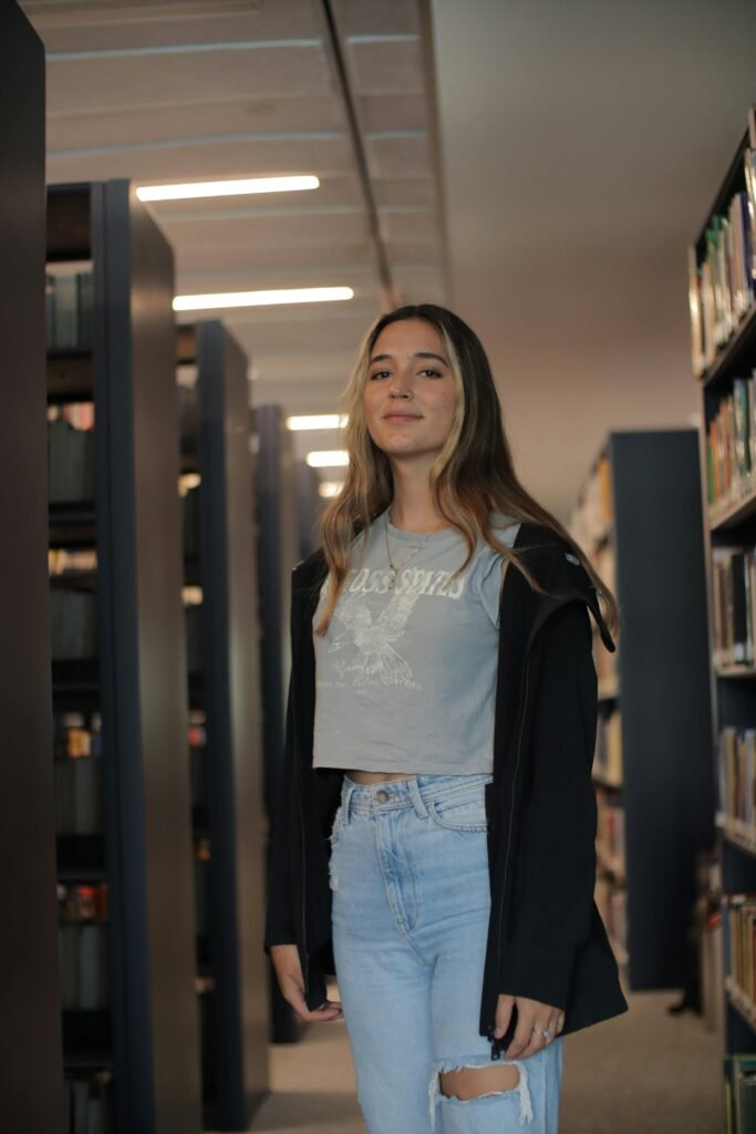 A young woman stands amidst library shelves, capturing the essence of learning.